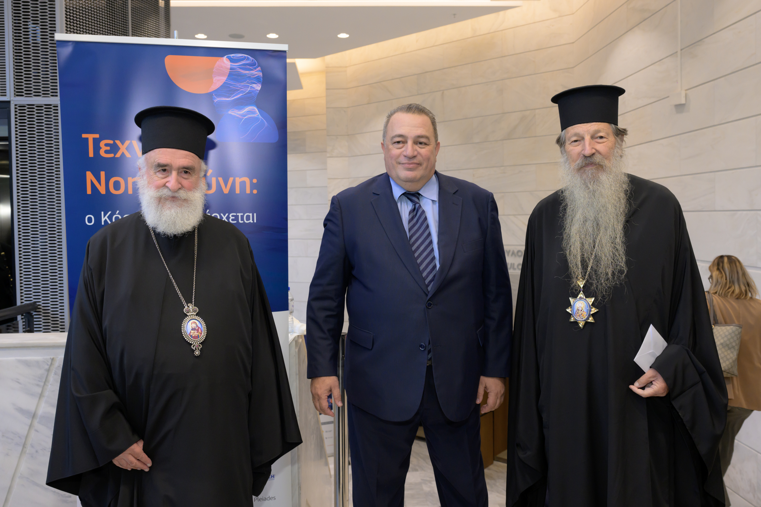 Τρία άτομα σε αναμνηστική φωτογραφία μπροστά από πανό.