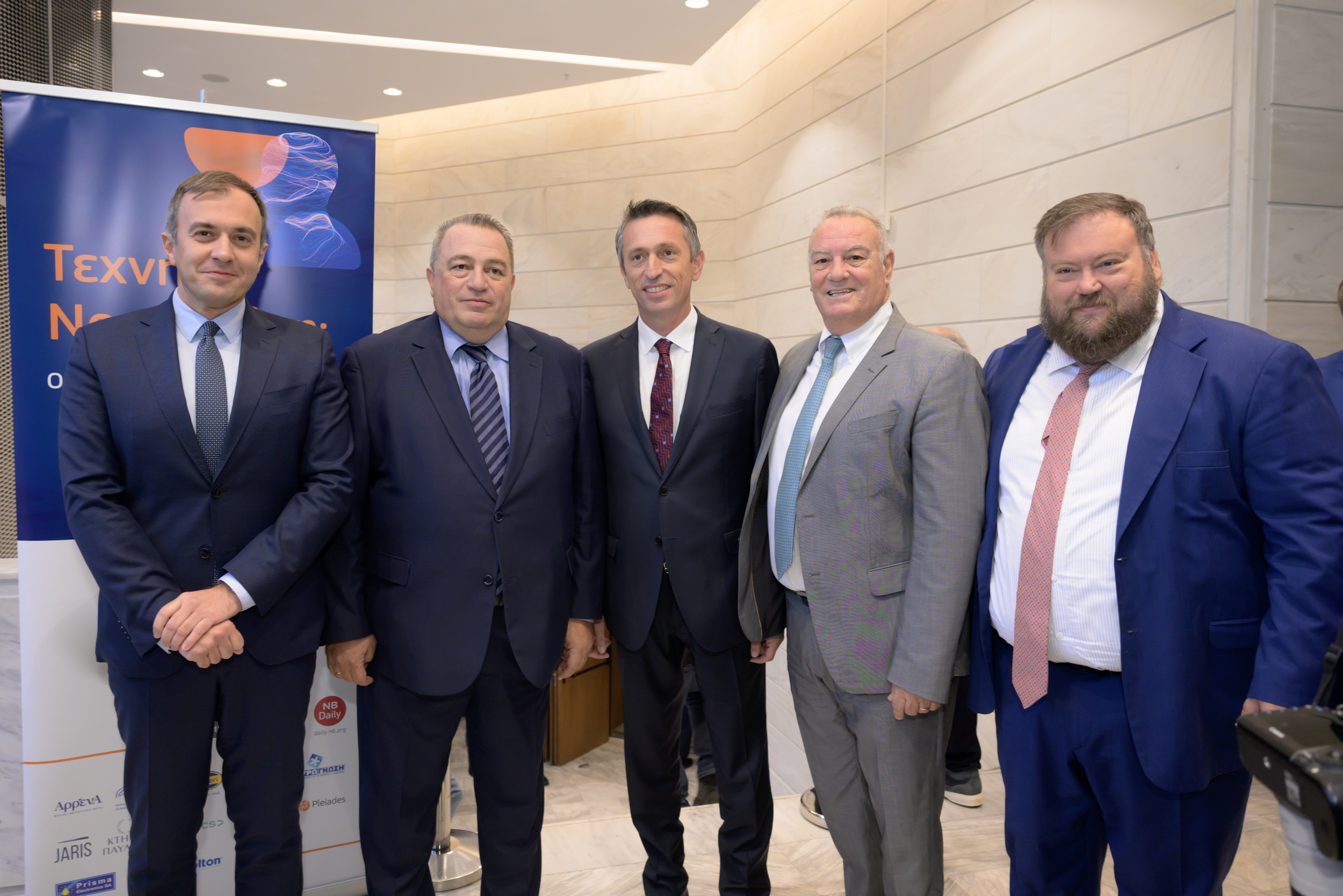 Πέντε άτομα φωτογραφίζονται στον χώρο υποδοχής της εκδήλωσης.